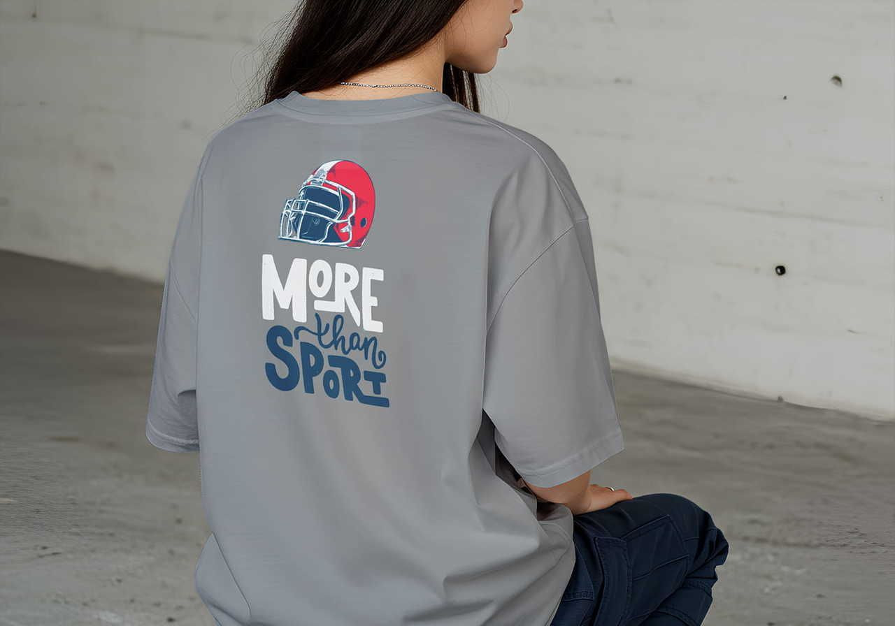 A woman with long hair sits sideways, wearing a gray shirt with a red football helmet graphic and the text 